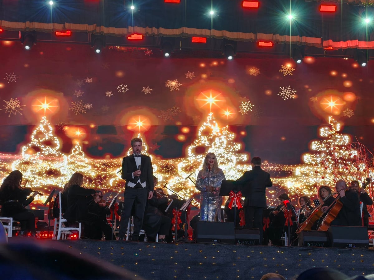 Un concierto de Nochebuena en la plaza Skanderbeg de Tirana, con el escenario iluminado y el público congregado alrededor.
