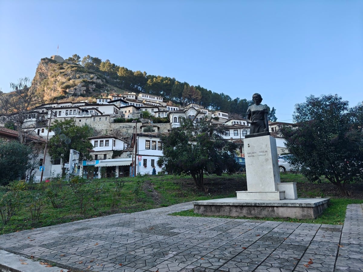 Estatua sobre un pedestal frente a las casas tradicionales de Berat.