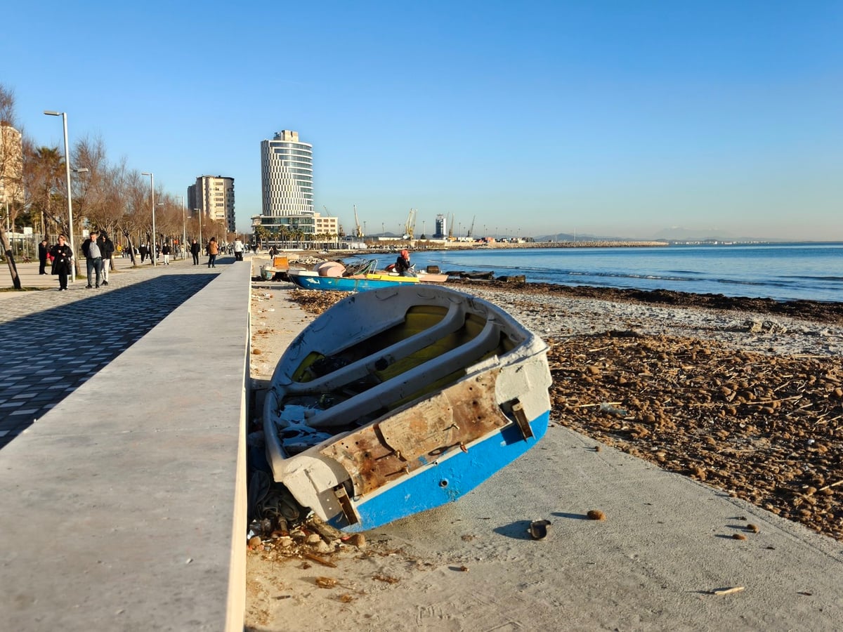 Paseo marítimo de Durrës con una barca varada junto a la costa.