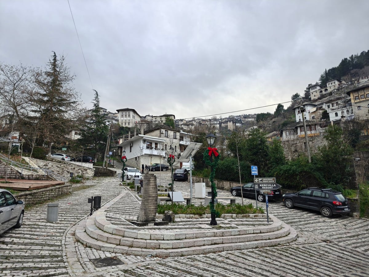 Plaza empedrada del casco histórico de Berat rodeada de casas tradicionales.