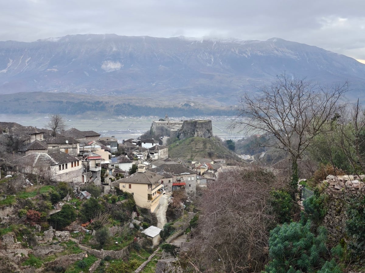 Vista de una ciudad histórica al pie de una montaña cubierta de nubes.