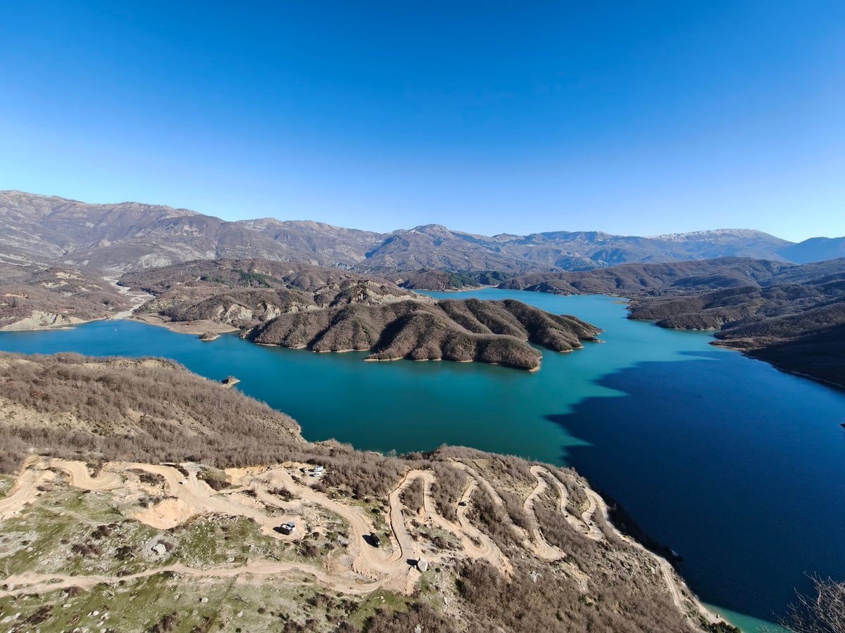 El lago de Bovilla rodeado de montañas, con el agua de un turquesa intenso represada entre las laderas de piedra caliza.