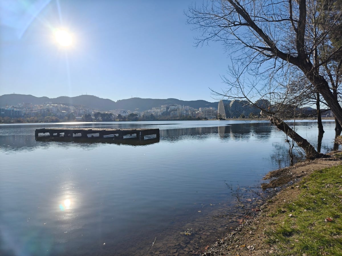 El lago artificial del Gran Parque de Tirana (Parku i Madh), con sus orillas arboladas y la superficie del agua en calma.
