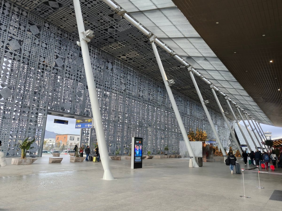 La fachada exterior del aeropuerto de Tirana, con el rótulo del aeropuerto y las pistas al fondo.