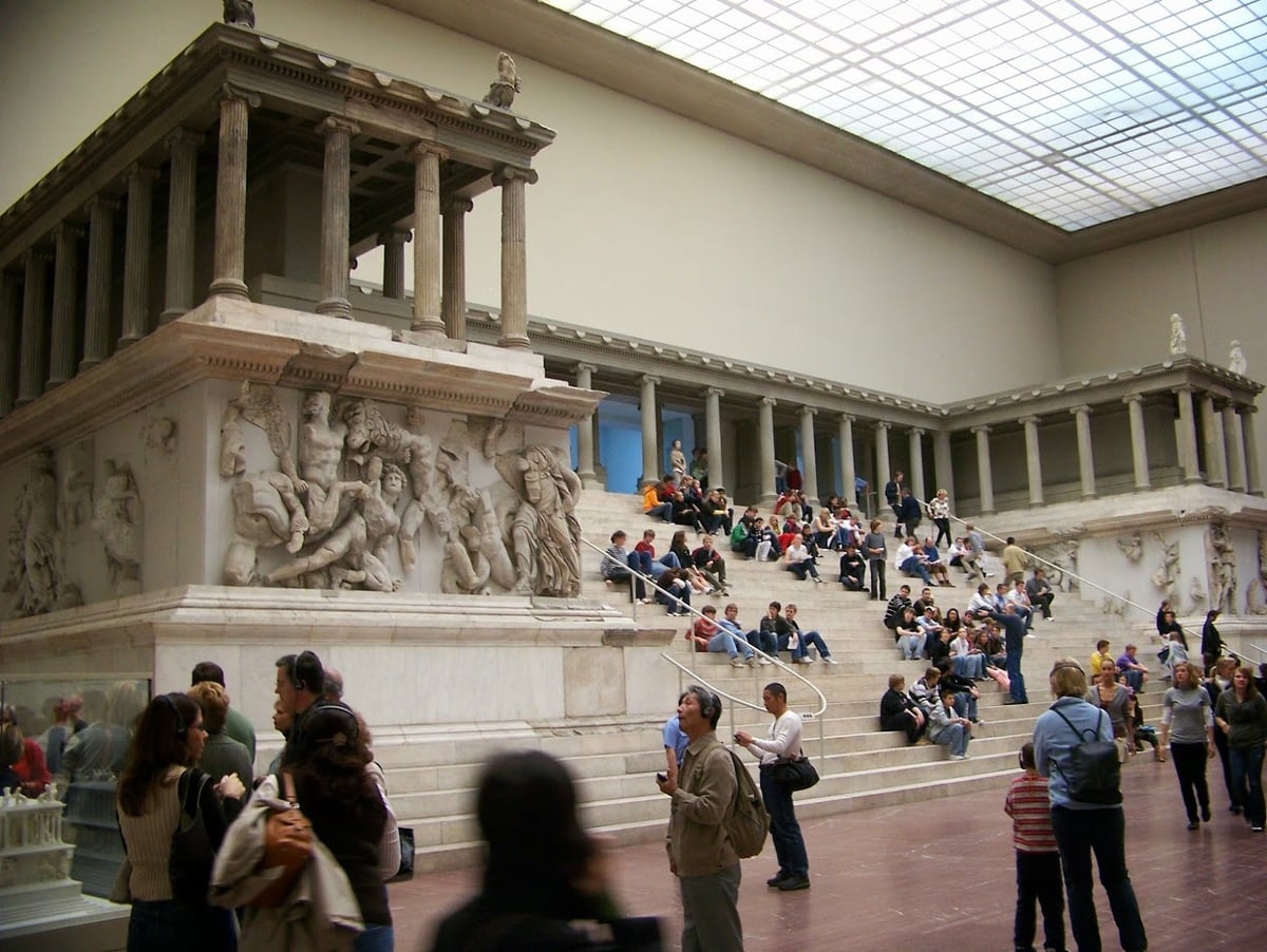 Sala del Museo de Pérgamo en Berlín con un antiguo altar monumental y visitantes.