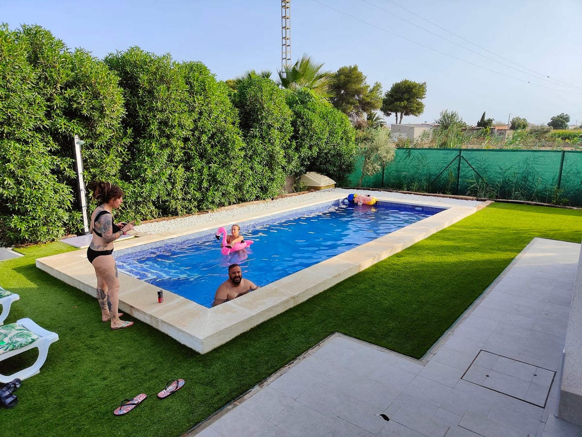 Piscina de una casa rodeada de césped y árboles