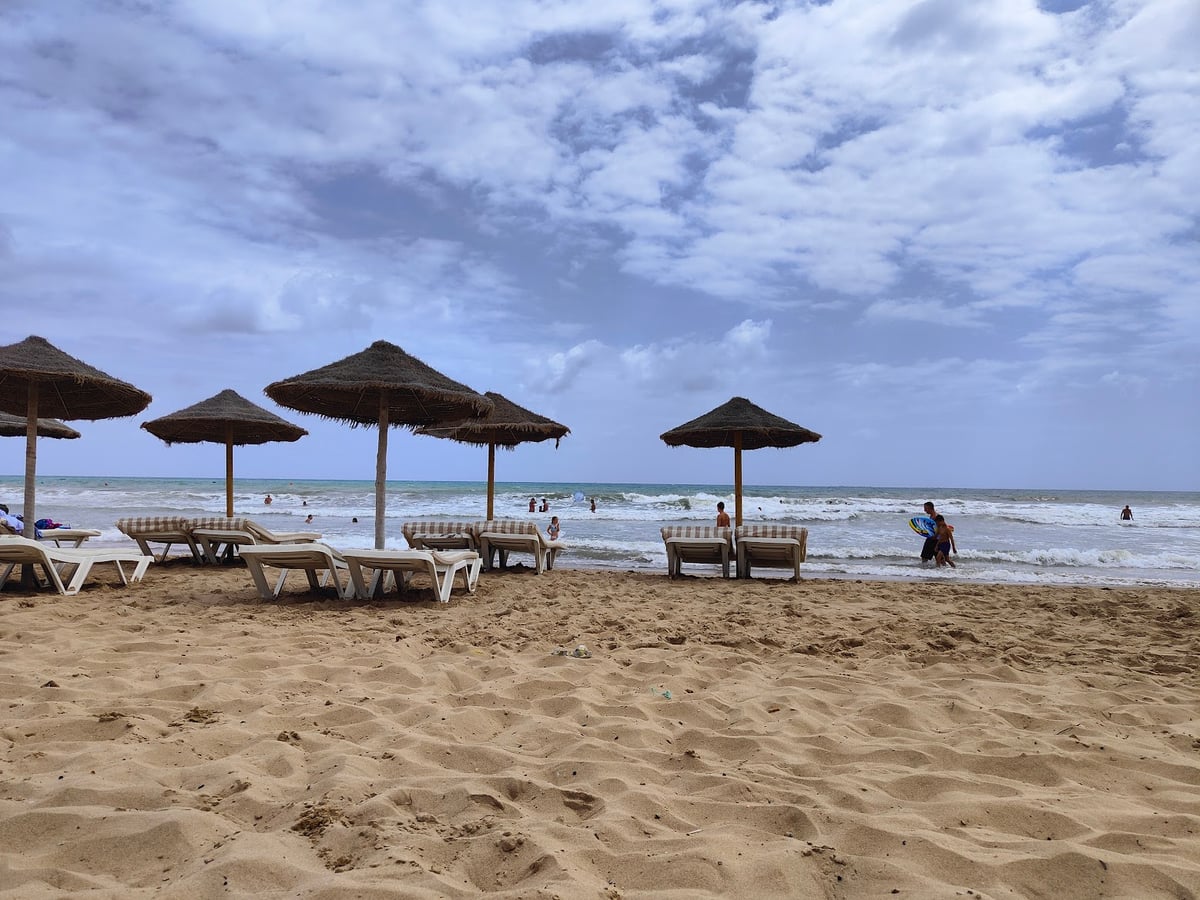 Playa de arena con sombrillas junto al mar