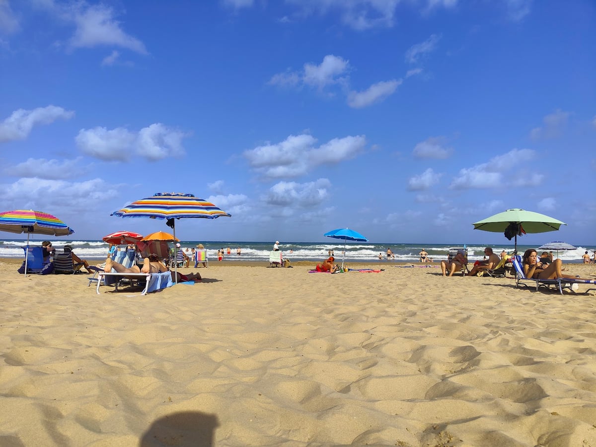Playa concurrida con sombrillas y bañistas