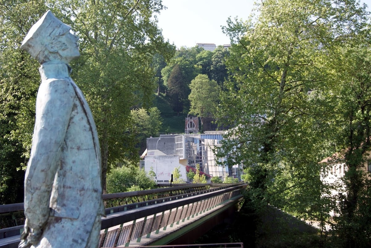 Estatua junto a un puente y vegetación