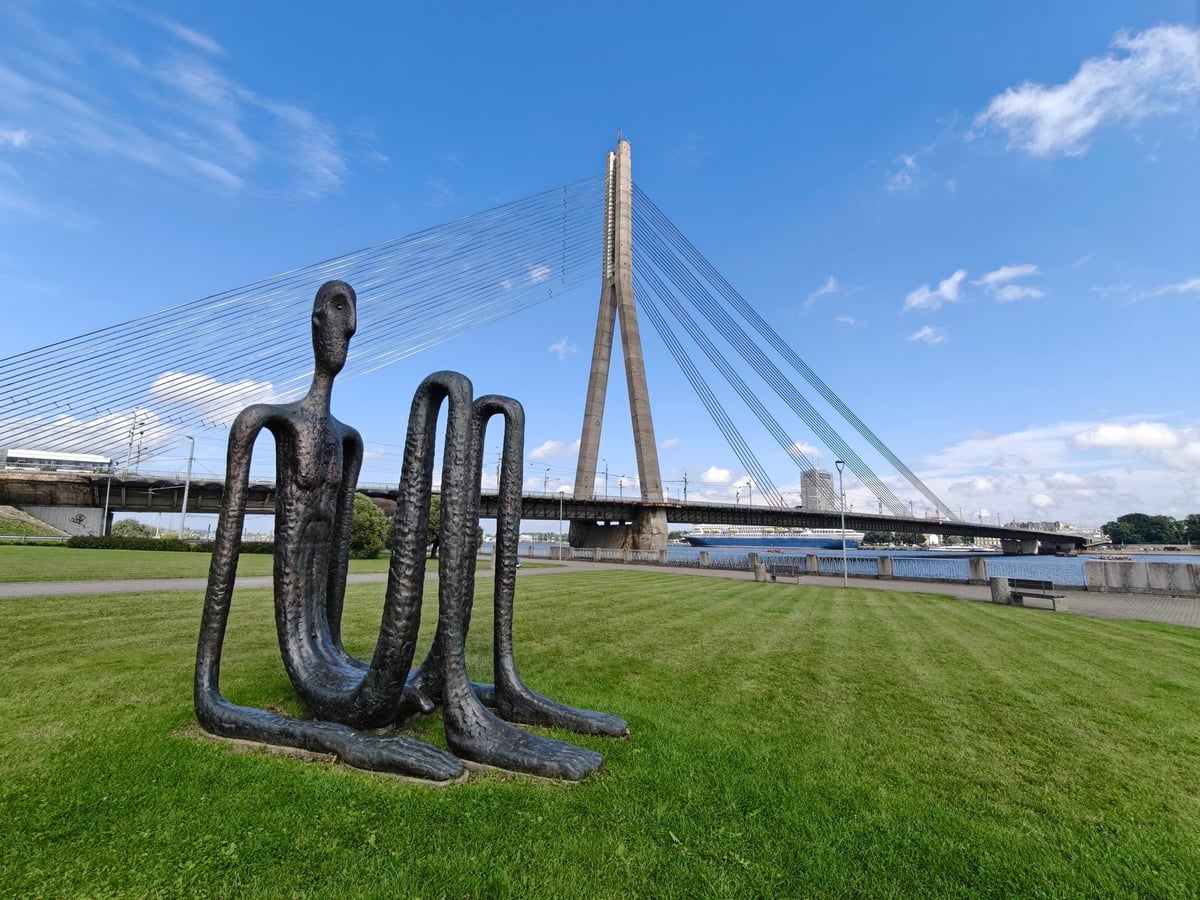 Estatua de la torre Riga Tower Counter, con el icónico puente Vanšu al fondo