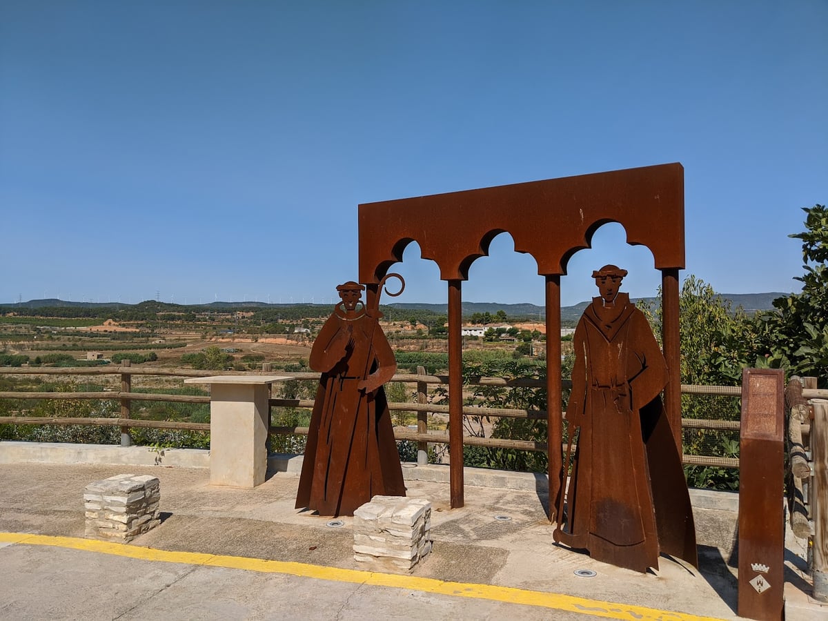 Escultura de figuras religiosas frente a un paisaje rural