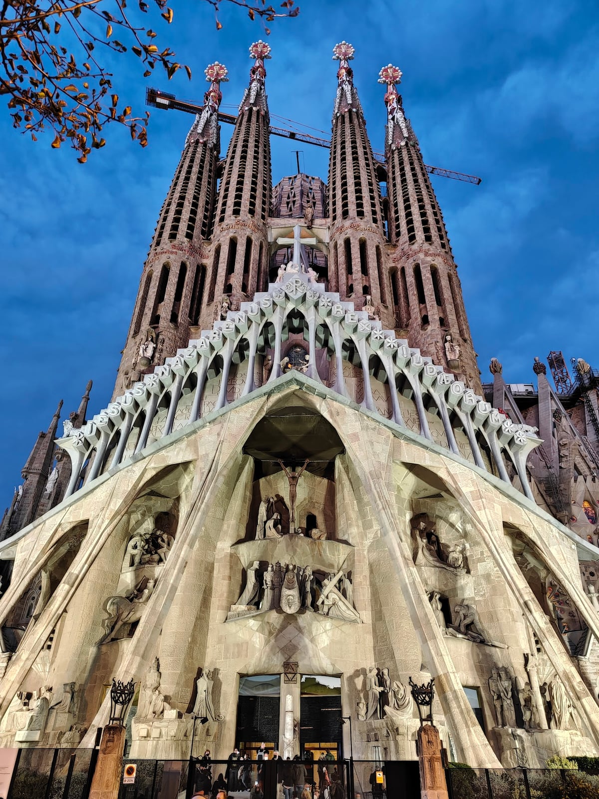 La fachada de la Pasión de la Sagrada Família al anochecer, con las cuatro torres iluminadas contra un cielo azul oscuro