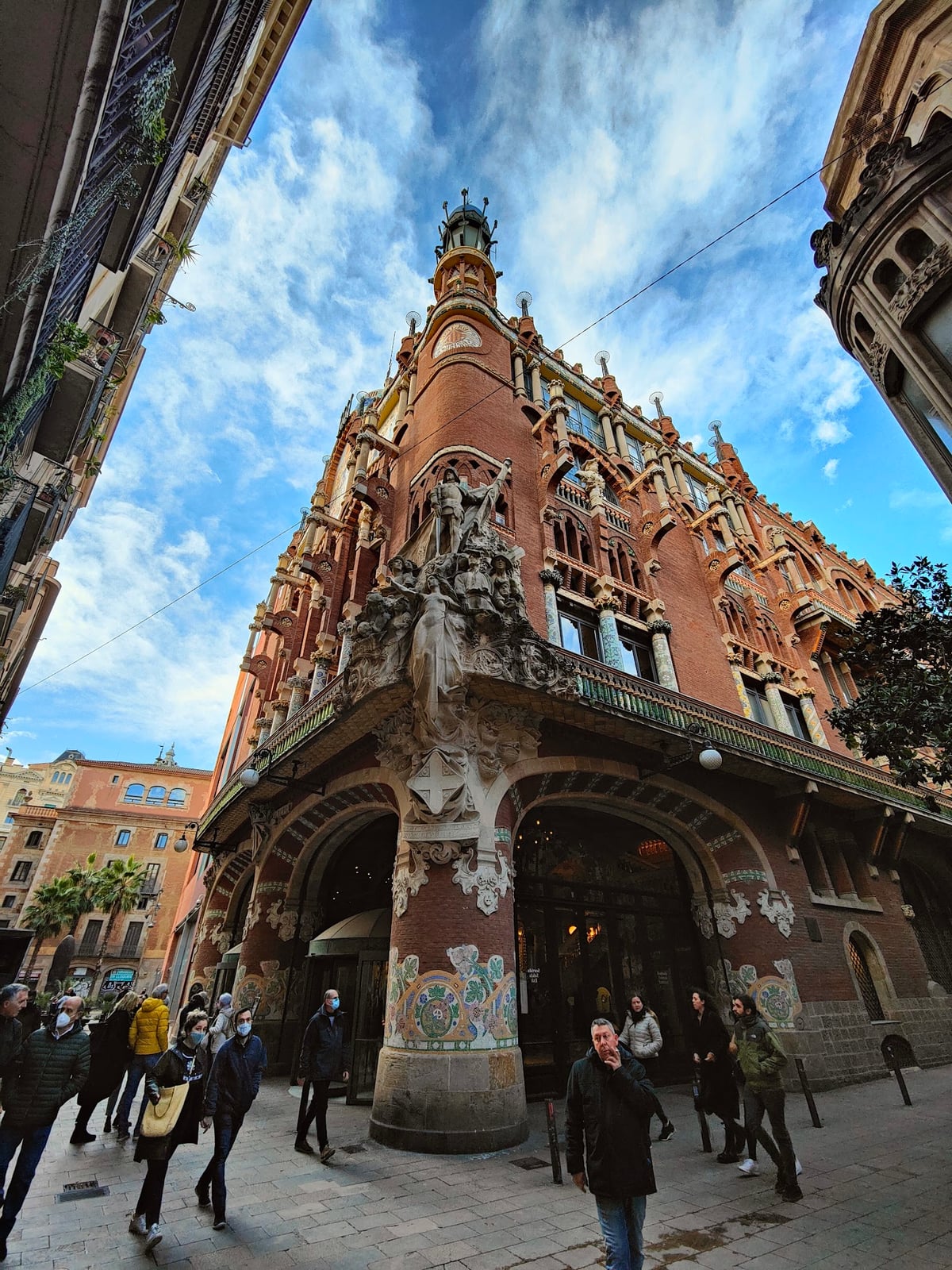 La fachada de ladrillo y mosaico del Palau de la Música Catalana, con su escultura de esquina, vista desde la calle