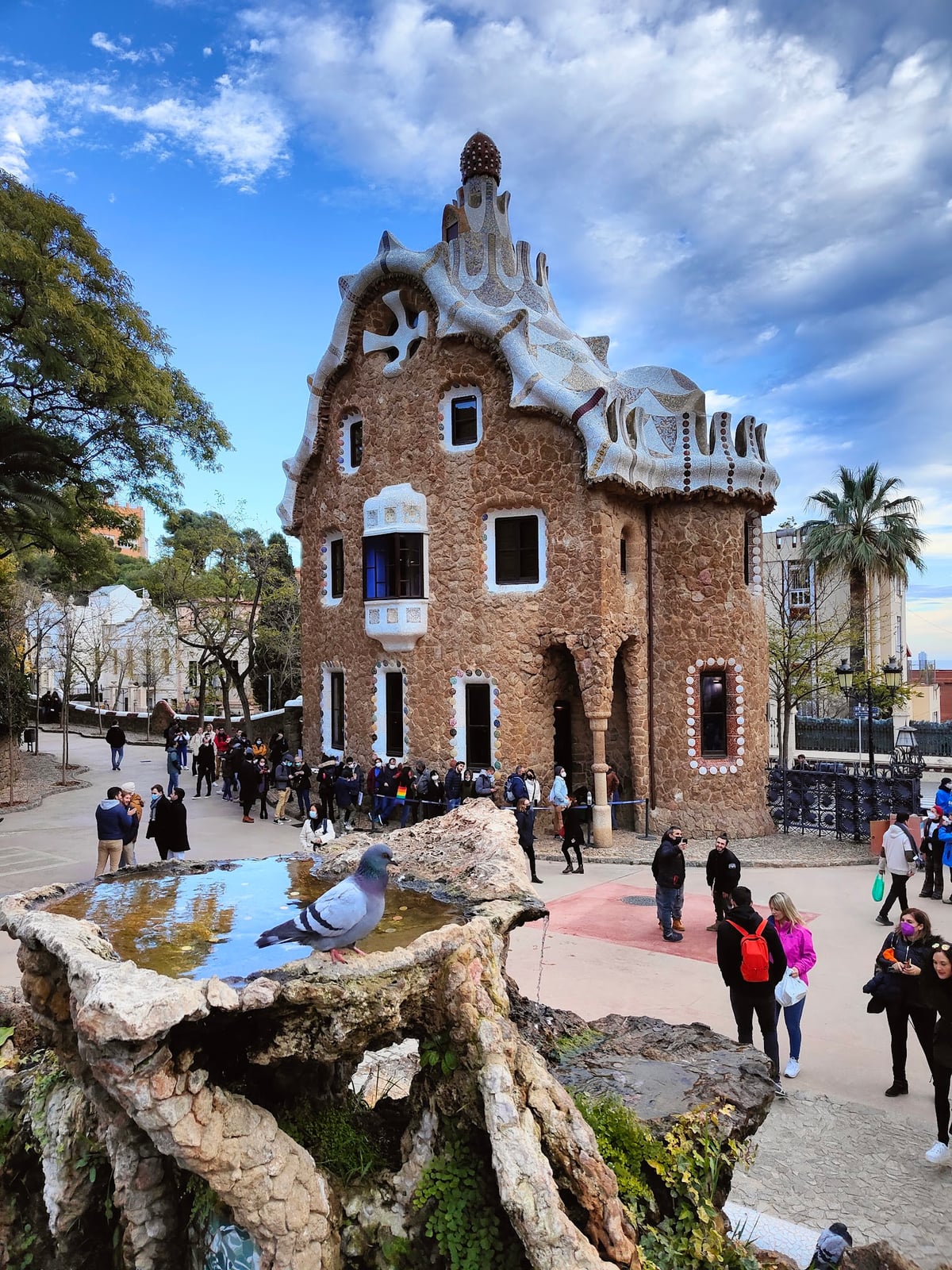 La Casa del Guarda de Park Güell, con su tejado de trencadís y la fuente de la salamandra en primer término, entre los visitantes que hacen cola