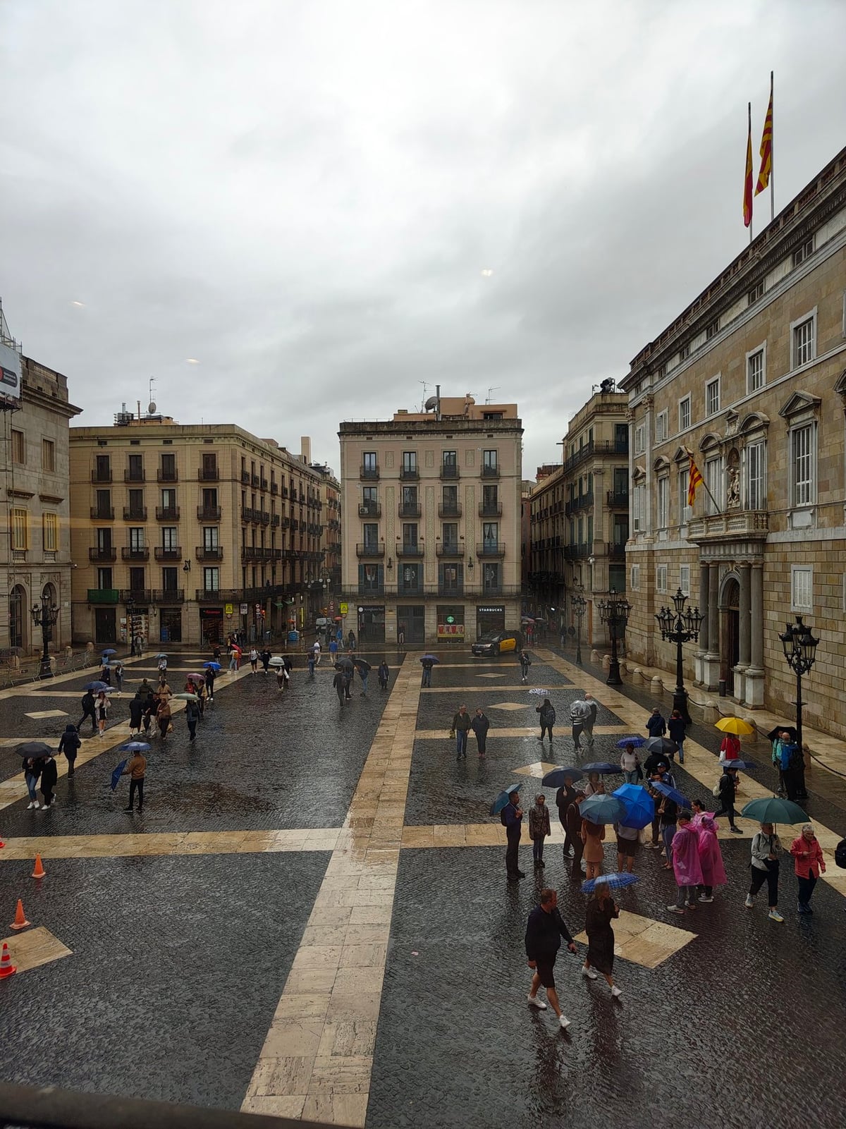 Plaza de Barcelona con edificios históricos y pavimento mojado