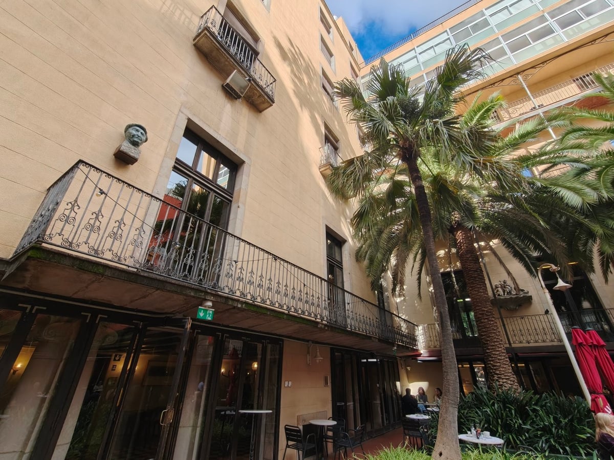 Fachada de un edificio histórico con balcones y palmeras
