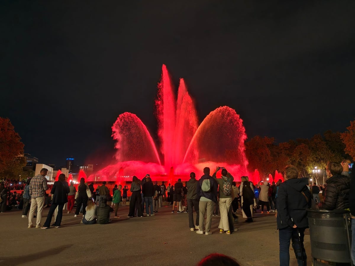 Los chorros de la Font Màgica iluminados de rojo, con el público en primer plano.