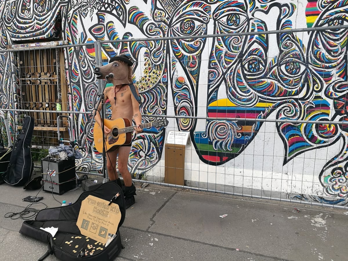Artista junto a un mural del Muro de Berlín