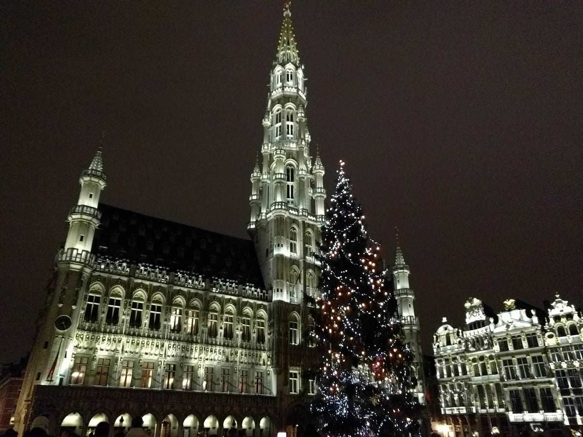 La Grand Place de Bruselas iluminada de noche con el mercado de Navidad instalado en el centro