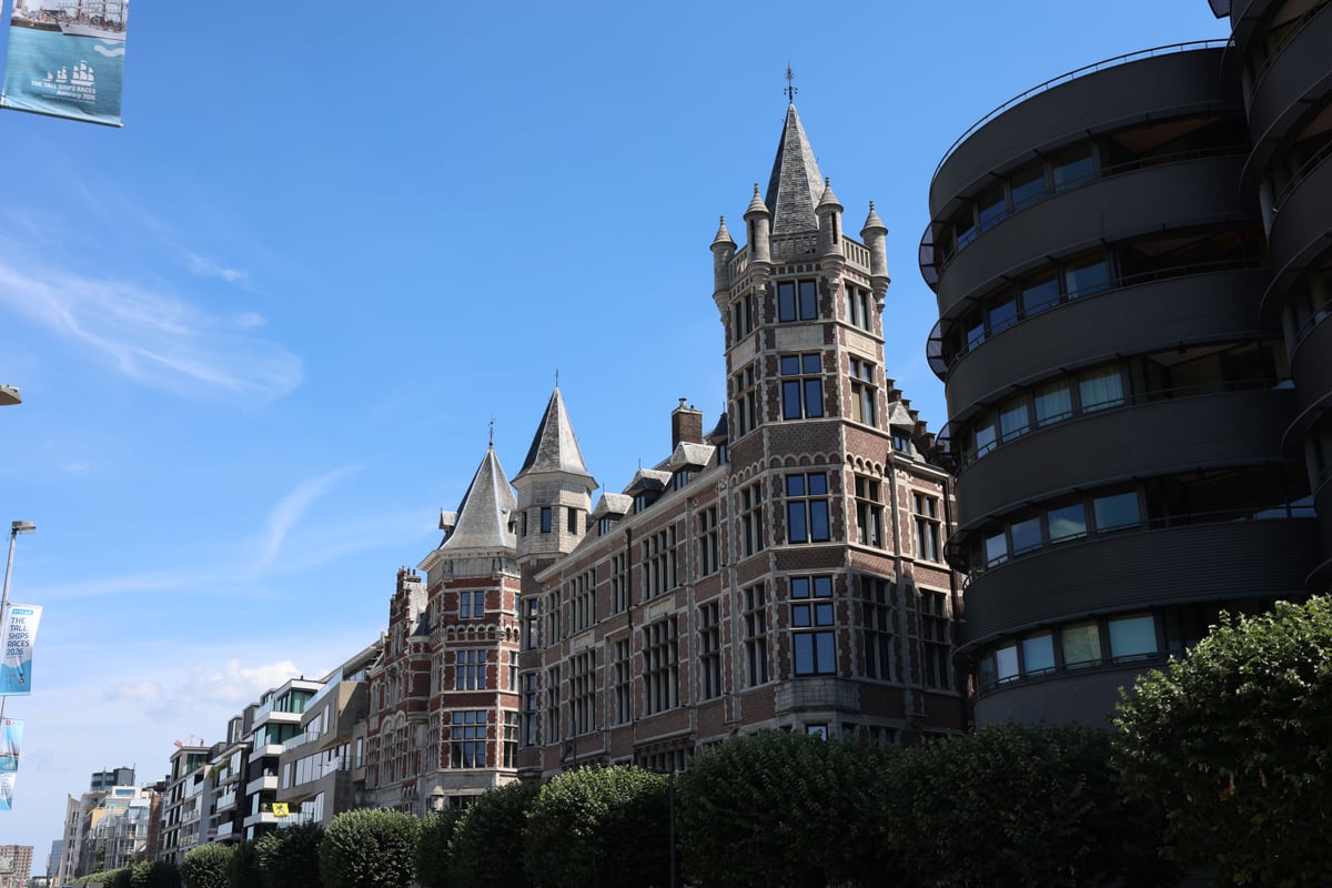 Edificios de estilo gótico bajo un cielo azul en el paisaje urbano de Amberes, que muestran el patrimonio arquitectónico europeo.