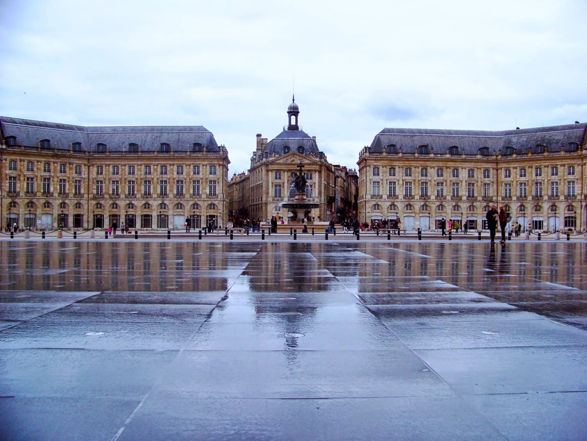 La Place de la Bourse de Burdeos reflejada en el Miroir d'eau, con sus fachadas neoclásicas simétricas.