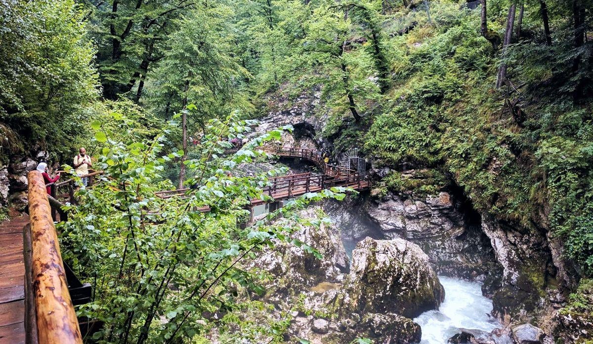 Pasarela de madera anclada a la pared de roca en la garganta de Vintgar, con el río Radovna corriendo verde por debajo entre rápidos.