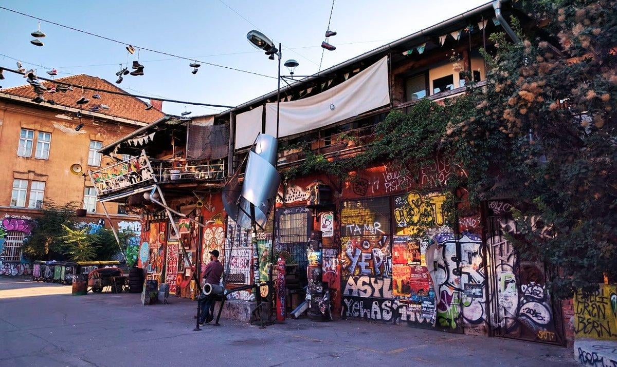 Fachada intervenida con murales y esculturas metálicas en el barrio de Metelkova, en Ljubljana, antiguo cuartel del ejército yugoslavo convertido en centro cultural.