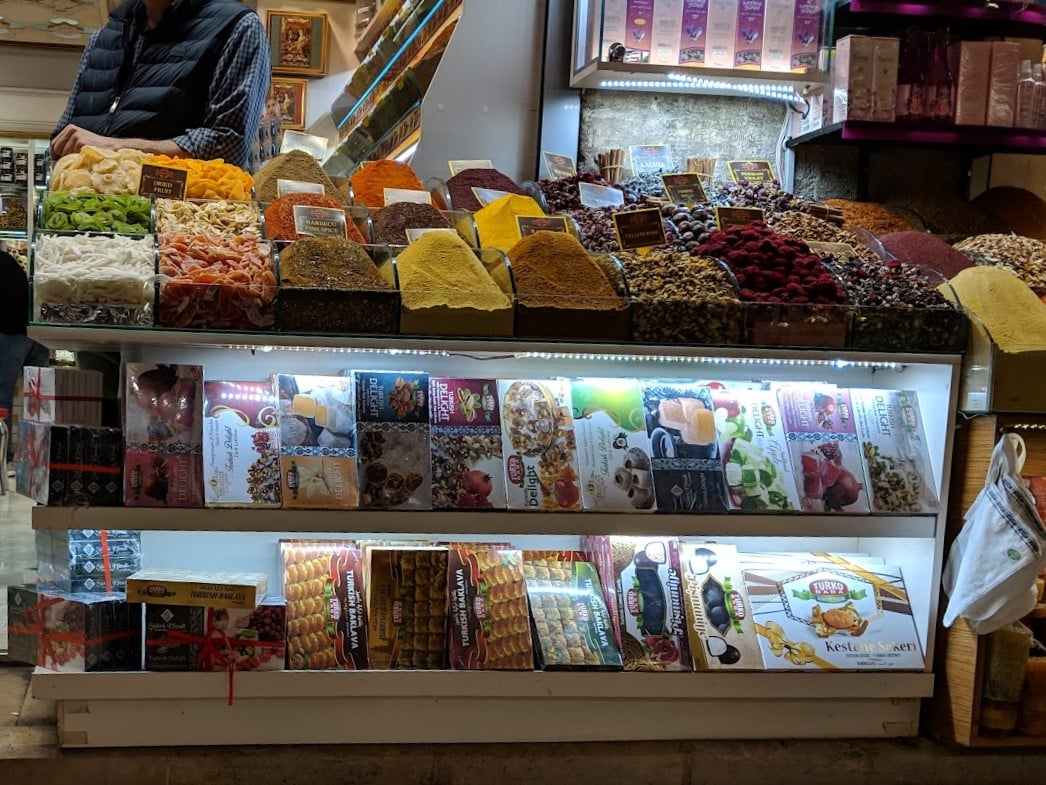 Puestos de especias y frutos secos en el Bazar de las Especias de Estambul, con los sacos de colores expuestos y las etiquetas de precio en liras.
