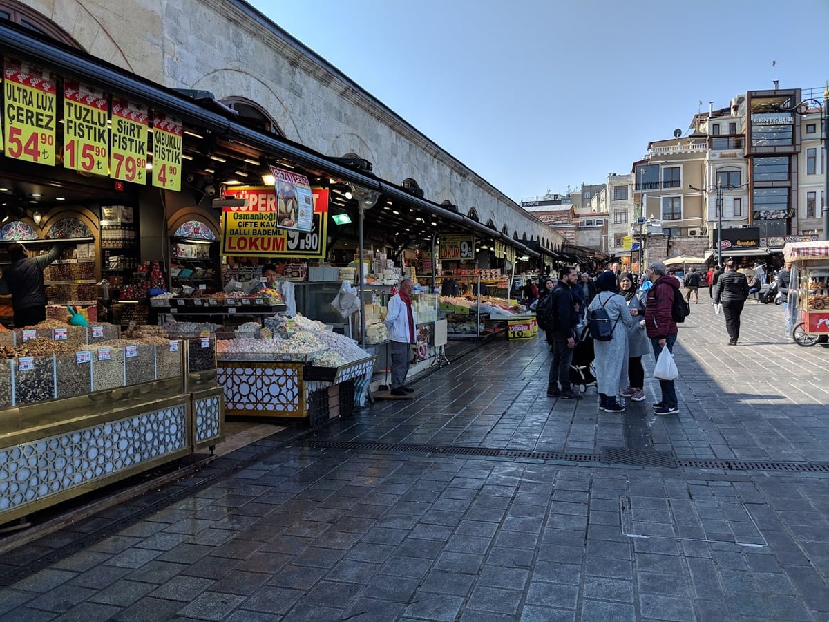 Los puestos de frutos secos y dulces adosados al muro exterior del Mercado Egipcio de Estambul, con carteles amarillos de precios en liras sobre los expositores y gente paseando por la explanada empedrada.