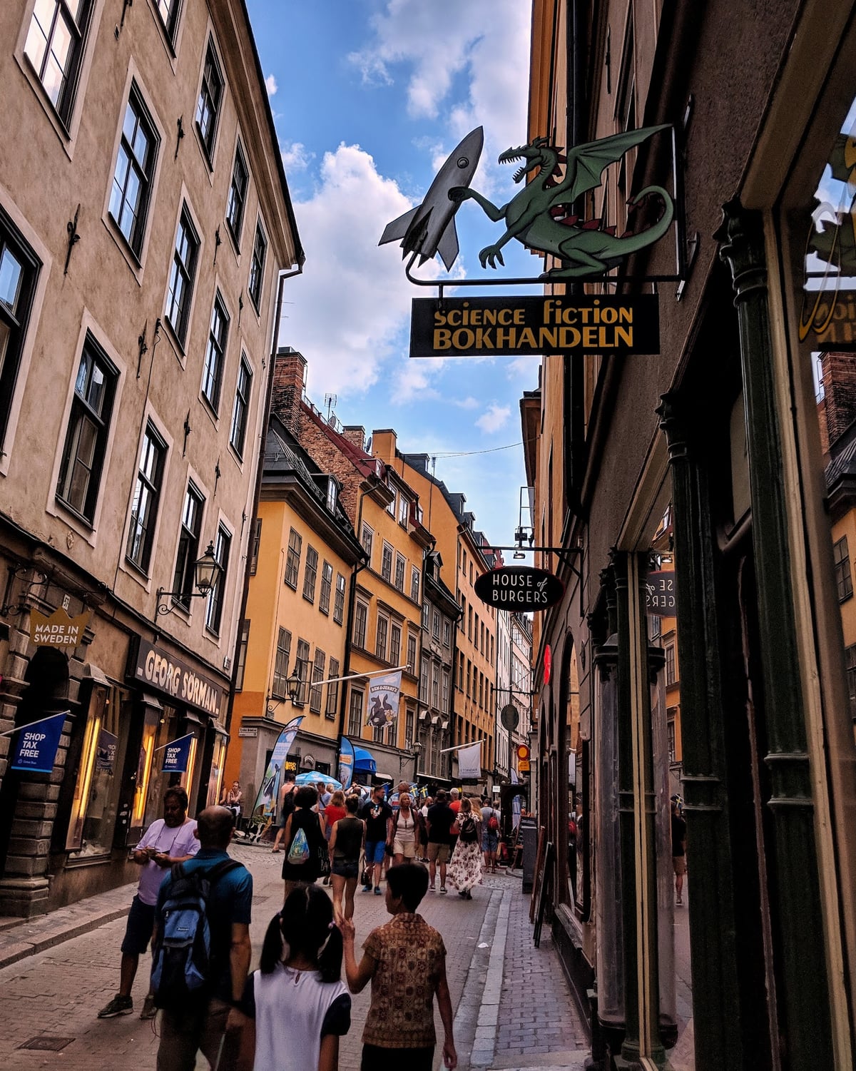 Una calle de Gamla Stan con fachadas de colores y el cartel de una librería con un dragón y un cohete