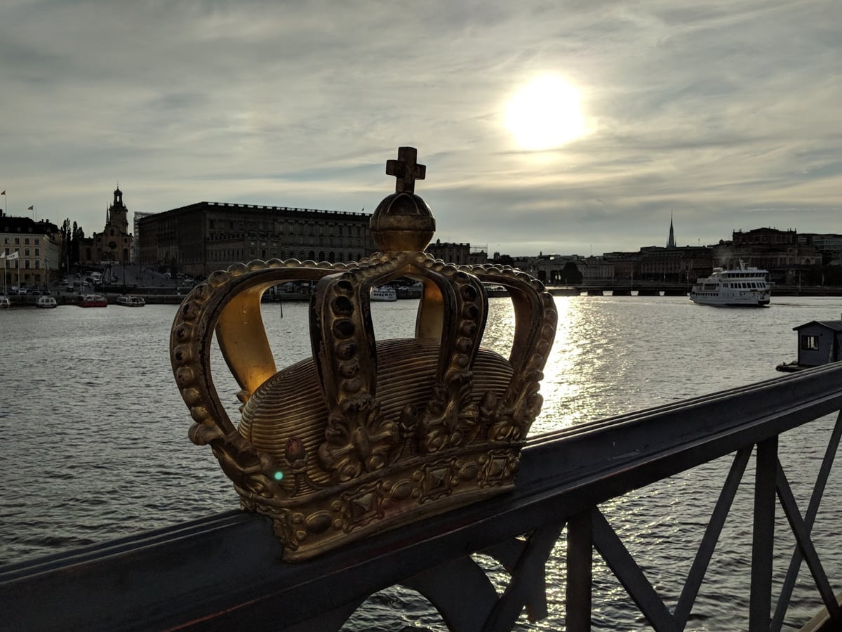 La corona dorada del mirador Utsiktspunkt enmarcando Gamla Stan y el Palacio Real al atardecer, con el sol reflejado en el agua