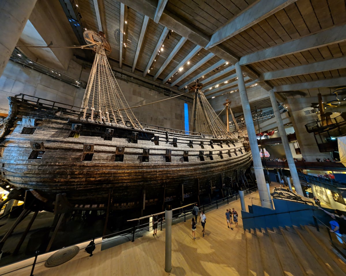 El casco del navío Vasa visto desde uno de los niveles superiores del museo, con visitantes recorriendo las pasarelas