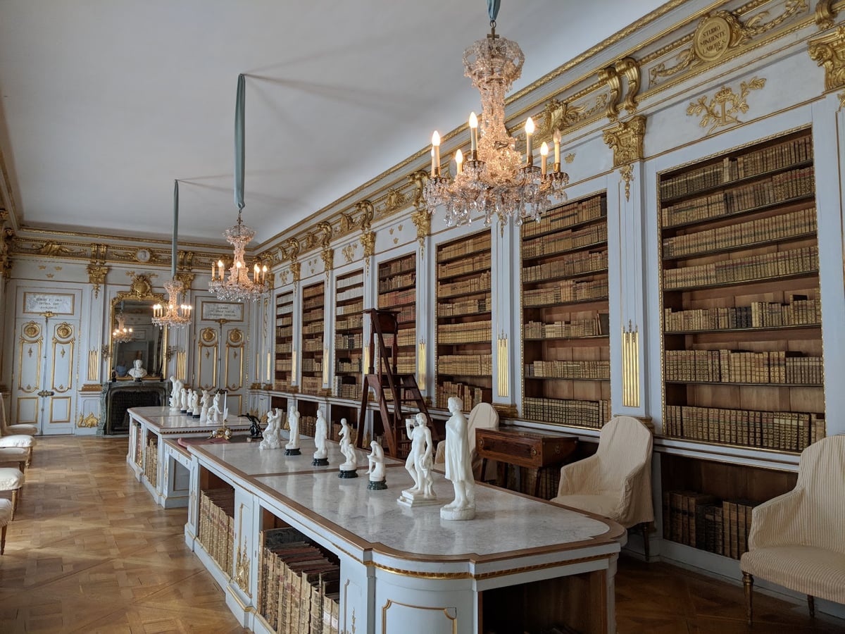 La fachada amarilla del palacio de Drottningholm vista desde los jardines, con la fuente y las estatuas en primer término