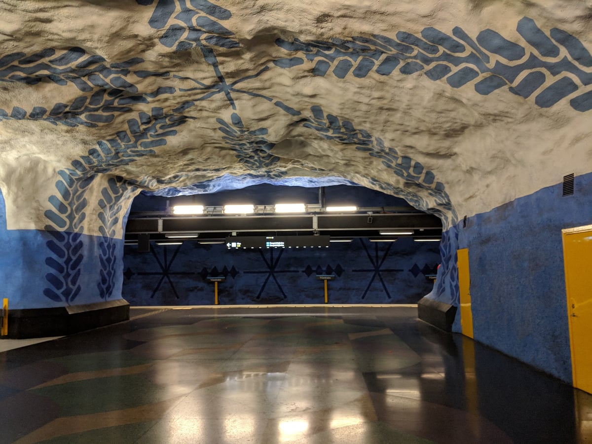 El andén de la línea azul de T-Centralen, con siluetas vegetales azules pintadas sobre la roca excavada del techo abovedado