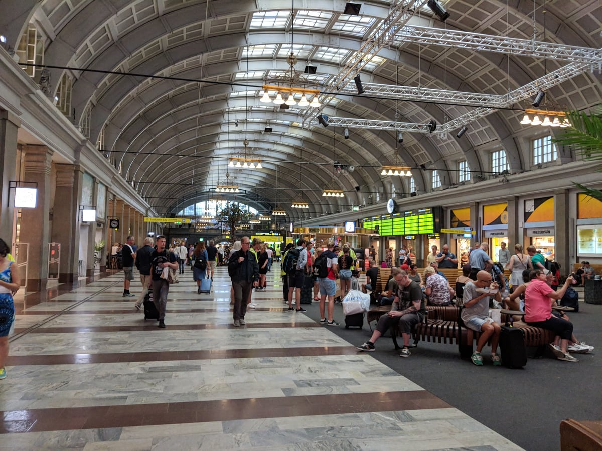 El interior de la Estación Central de Estocolmo, con su techo abovedado acristalado y viajeros cruzando el vestíbulo hacia los andenes