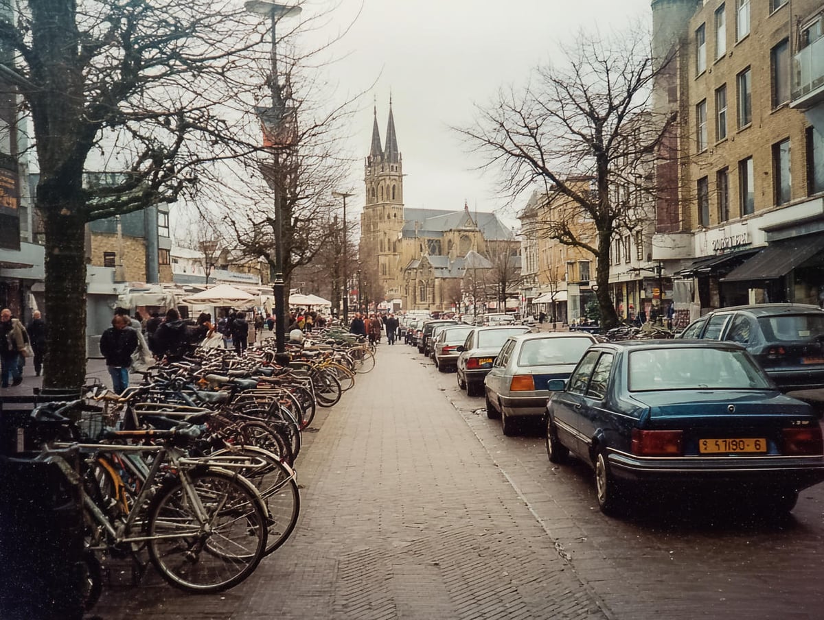 Calle comercial de una ciudad holandesa en invierno, con decenas de bicicletas aparcadas en batería a un lado, coches de los noventa al otro y las dos agujas de una iglesia gótica cerrando el fondo.