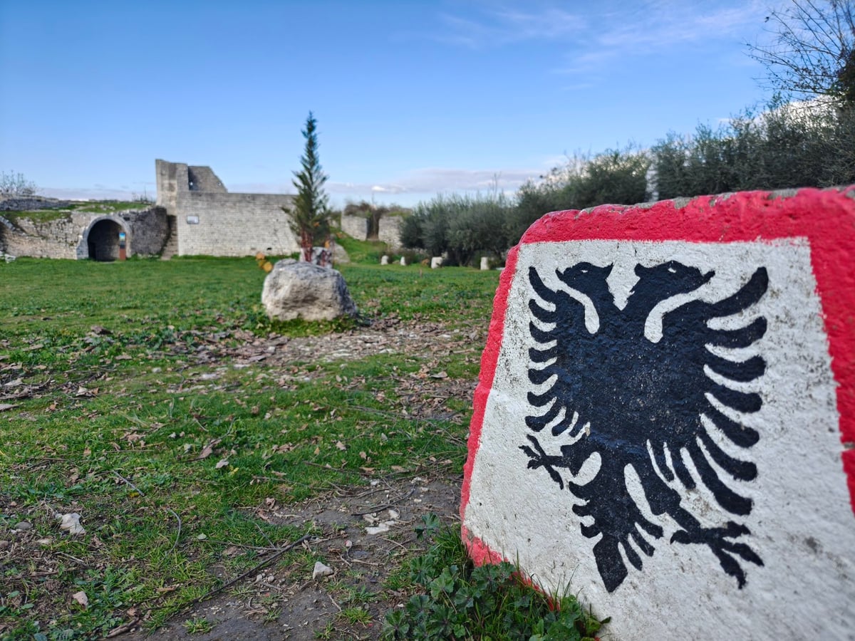 El castillo de Berat con una roca con la bandera de Albania pintada en primer plano.