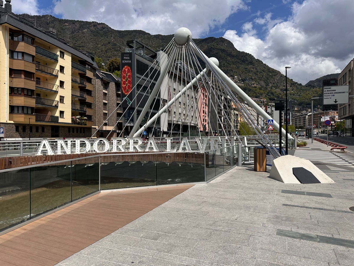 Puente icónico en Andorra la Vella con montañas y arquitectura urbana bajo un cielo nublado.