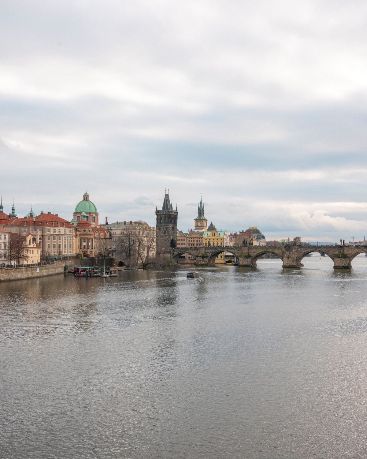 Vista panorámica del Puente de Carlos con edificios históricos a lo largo del río Moldava en Praga.