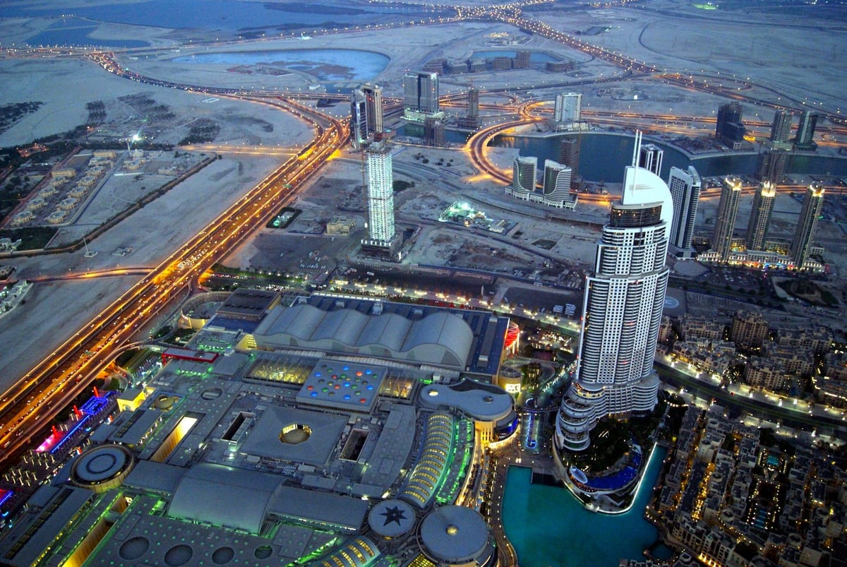 Vista aérea nocturna del centro de Dubái, destacando la zona de Downtown Dubai con el complejo de The Dubai Mall y las autopistas iluminadas como la avenida Sheikh Zayed.