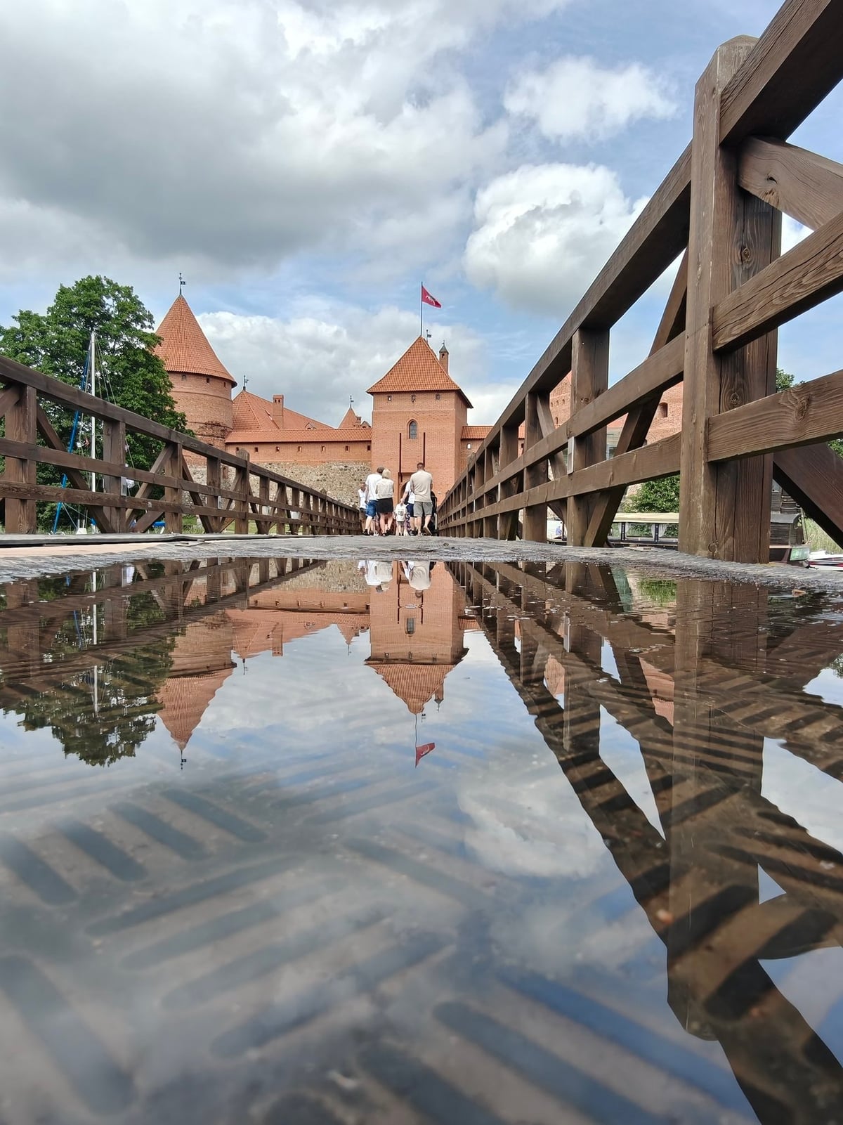 El histórico Castillo de Trakai reflejado en el agua, capturado desde uno de sus puentes de madera.