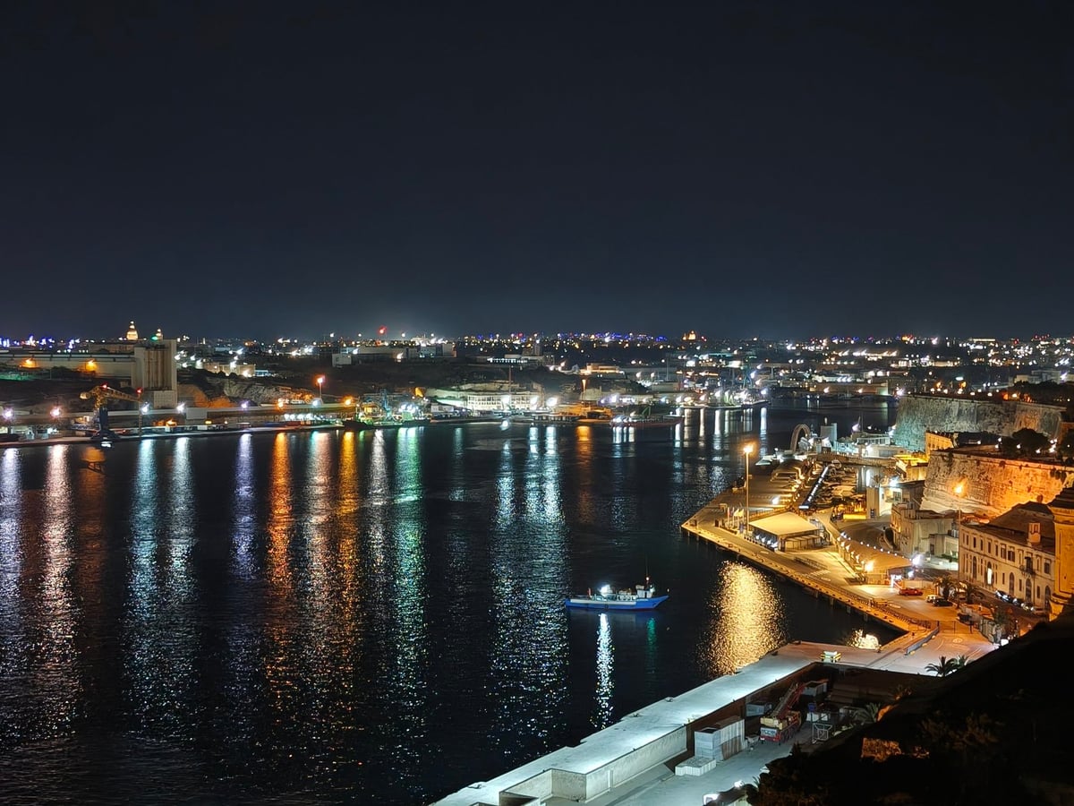 Vista nocturna del Gran Puerto (Grand Harbour) en La Valeta, la capital de Malta, con luces reflejándose en el agua y la arquitectura histórica de la ciudad iluminada de fondo