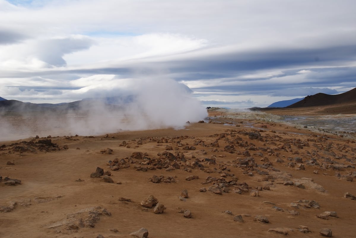 El campo geotérmico de Hverir, con pozas de barro burbujeando y columnas de vapor sobre un suelo teñido de rojo y amarillo.