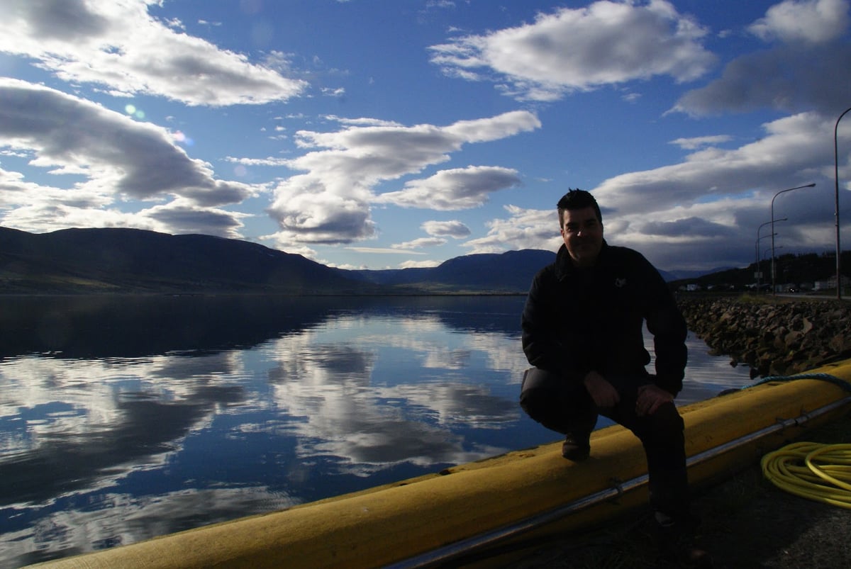 El fiordo Eyjafjörður al atardecer, con las montañas reflejándose en el agua en calma junto a Akureyri.