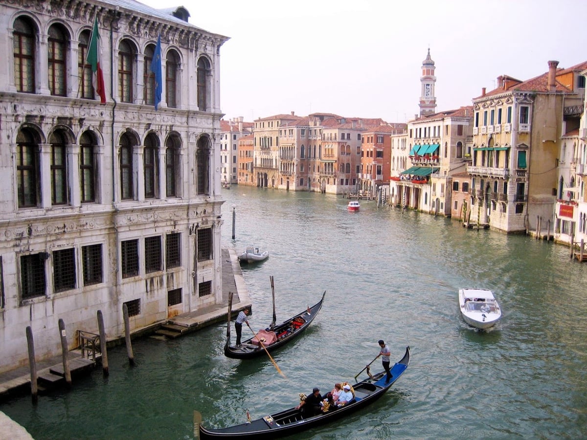 Foto de un canal de venecia con góndolas en primer plano