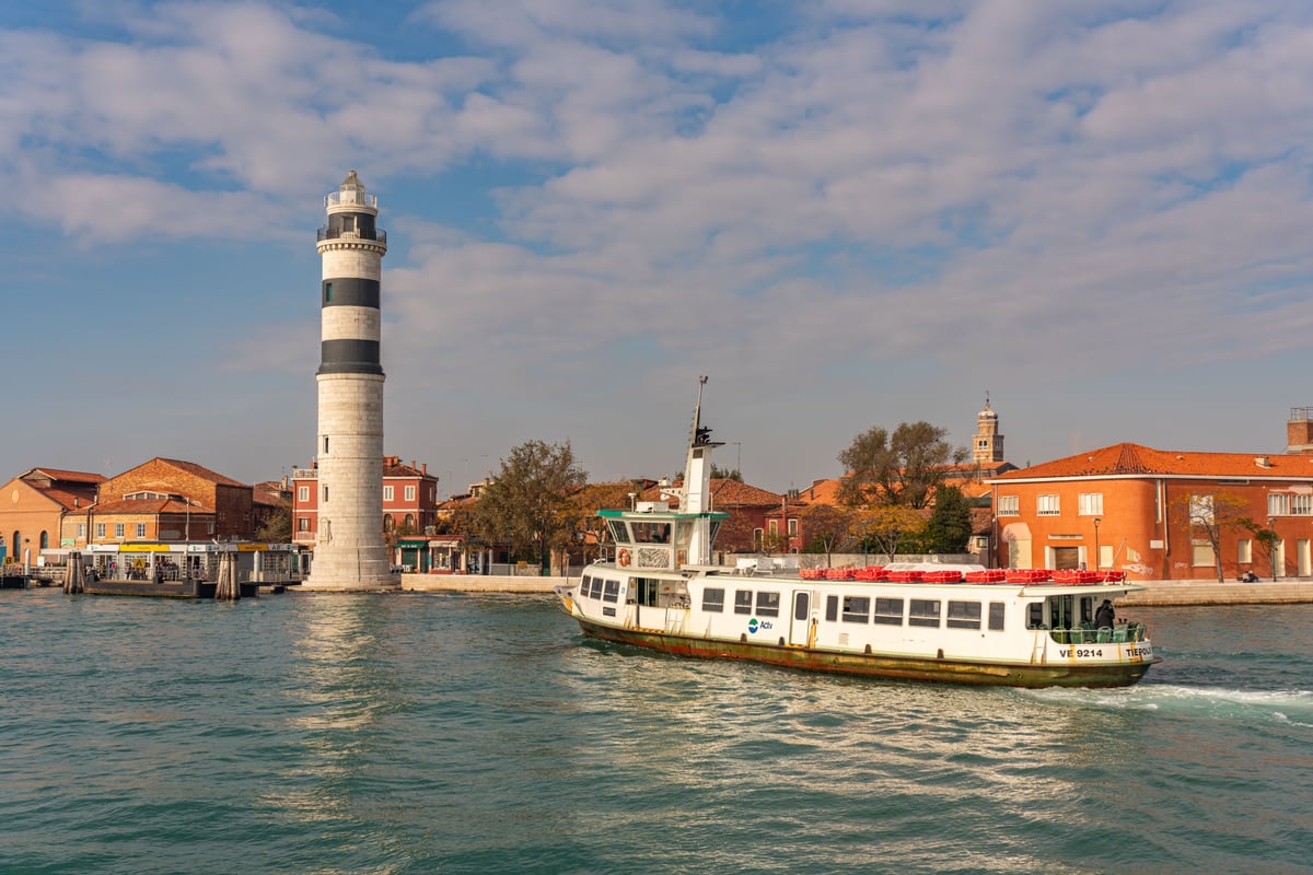 Encantadora vista de Murano con faro y transbordador navegando por las aguas venecianas.