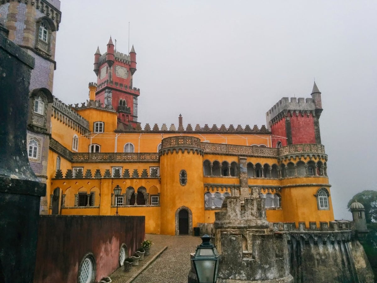 El Palacio da Pena de Sintra sobre su peñasco, con sus torres pintadas en amarillo y terracota emergiendo entre la niebla y el bosque de la sierra.