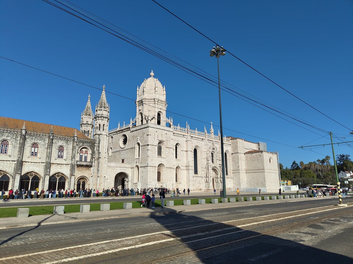 El claustro de dos plantas del Monasterio de los Jerónimos, con sus arcos y tracerías manuelinas labradas en piedra clara bajo la luz del mediodía.