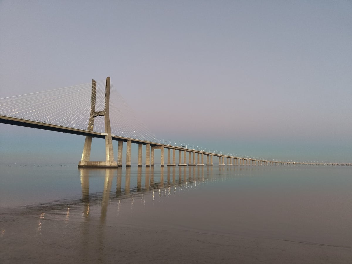 El puente Vasco da Gama sobre el Tajo visto desde la ribera del Parque das Nações, con su pilono atirantado y la sucesión de vanos perdiéndose en la bruma.