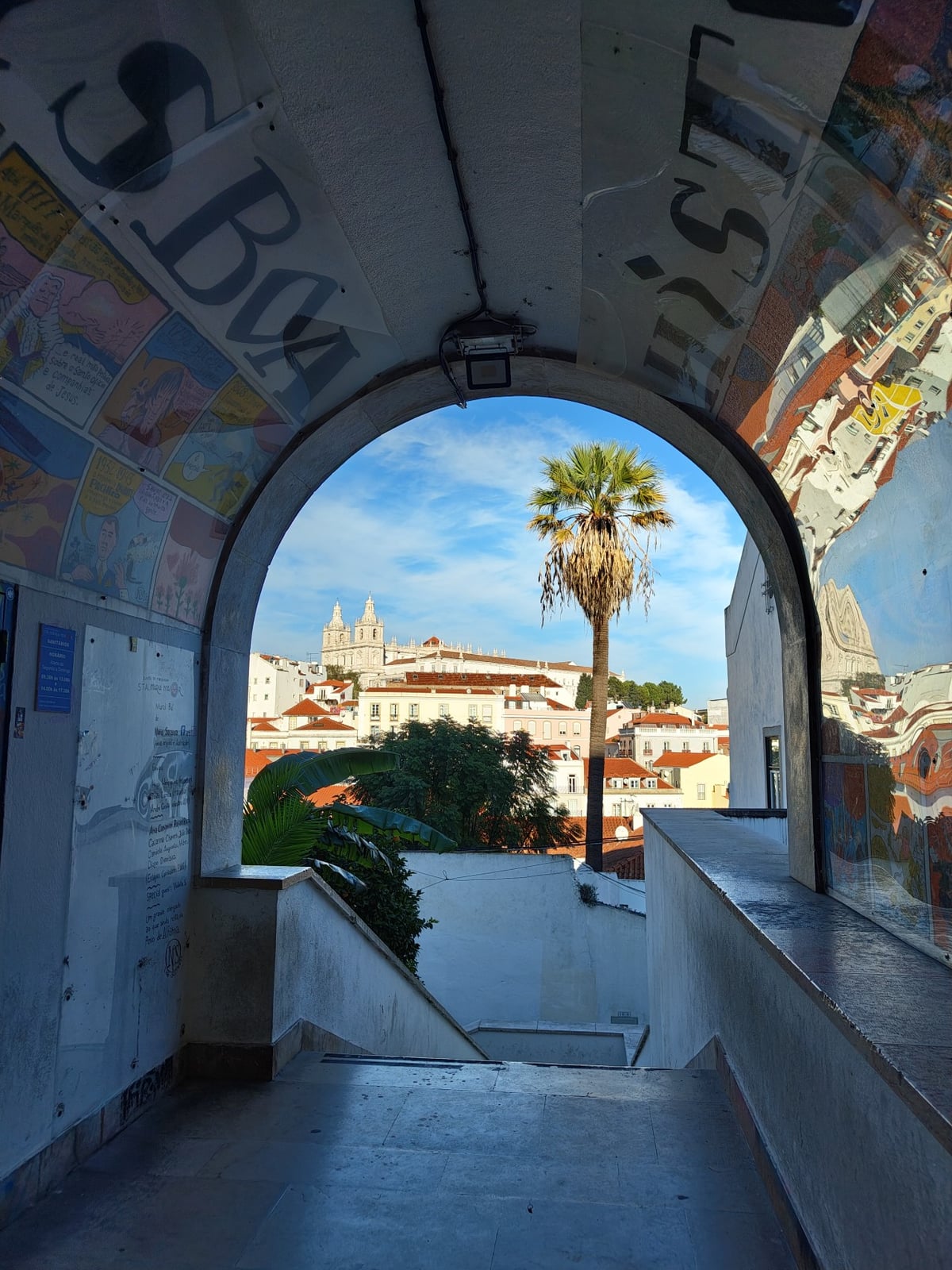 Vista de los tejados rojos de Alfama bajando hacia el Tajo desde uno de los miradores altos de Lisboa, con el río abriéndose al fondo.